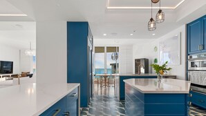 A modern kitchen with blue cabinets, a white countertop, and a patterned floor.