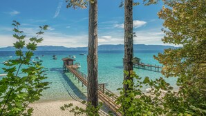 Ein Strand mit klarem türkisblauem Wasser, einer Holzsteg und ein kleines Holgebäude.