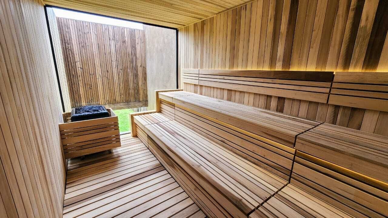A sauna with wooden benches and a bench with a black cushion.