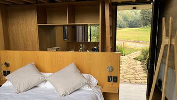 A modern bedroom with a large bed, wooden headboard, and a view of the outdoors.