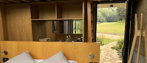 A modern bedroom with a large bed, wooden headboard, and a view of the outdoors.