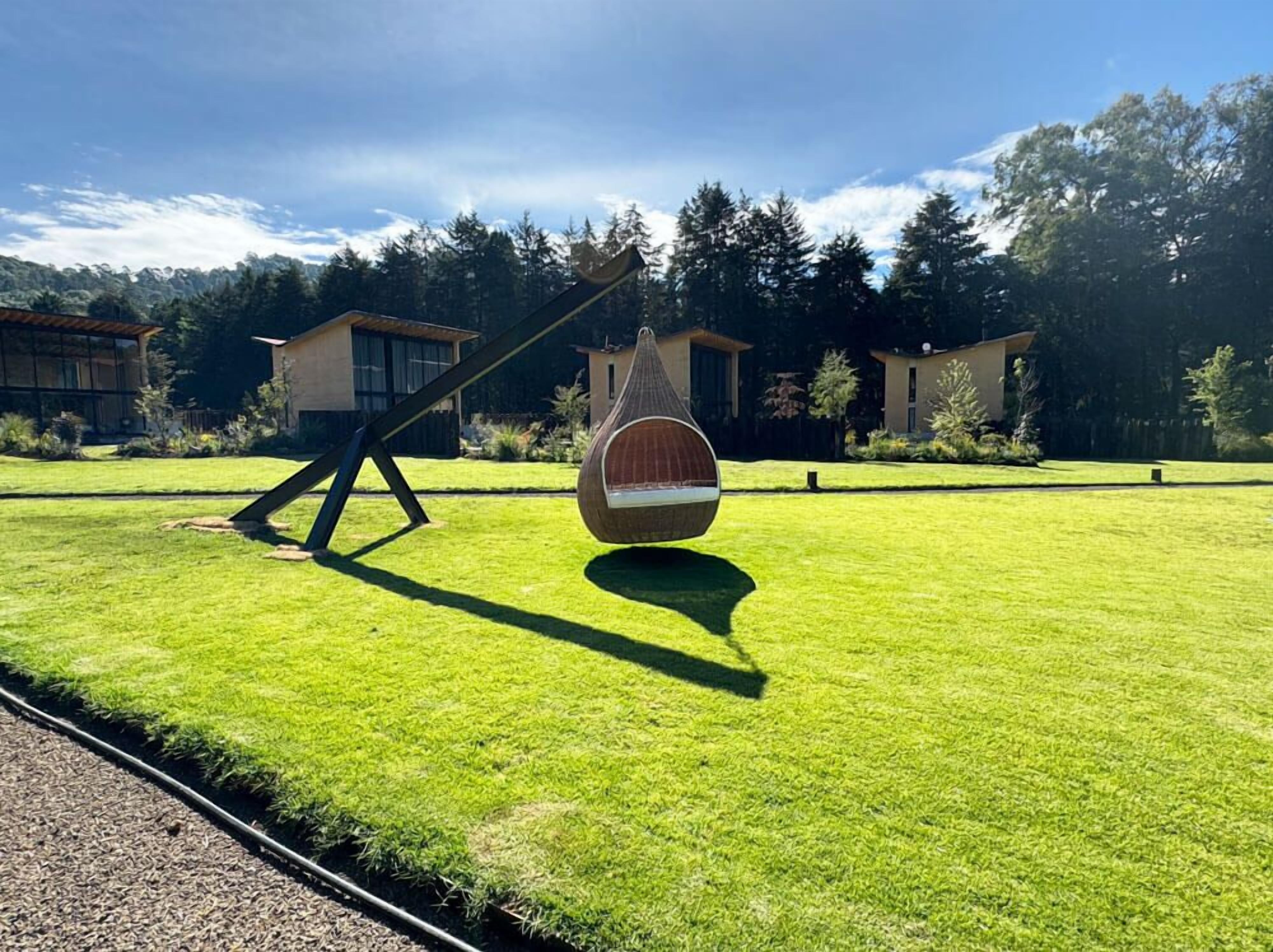 A well-maintained lawn with a hammock chair and a swing set.