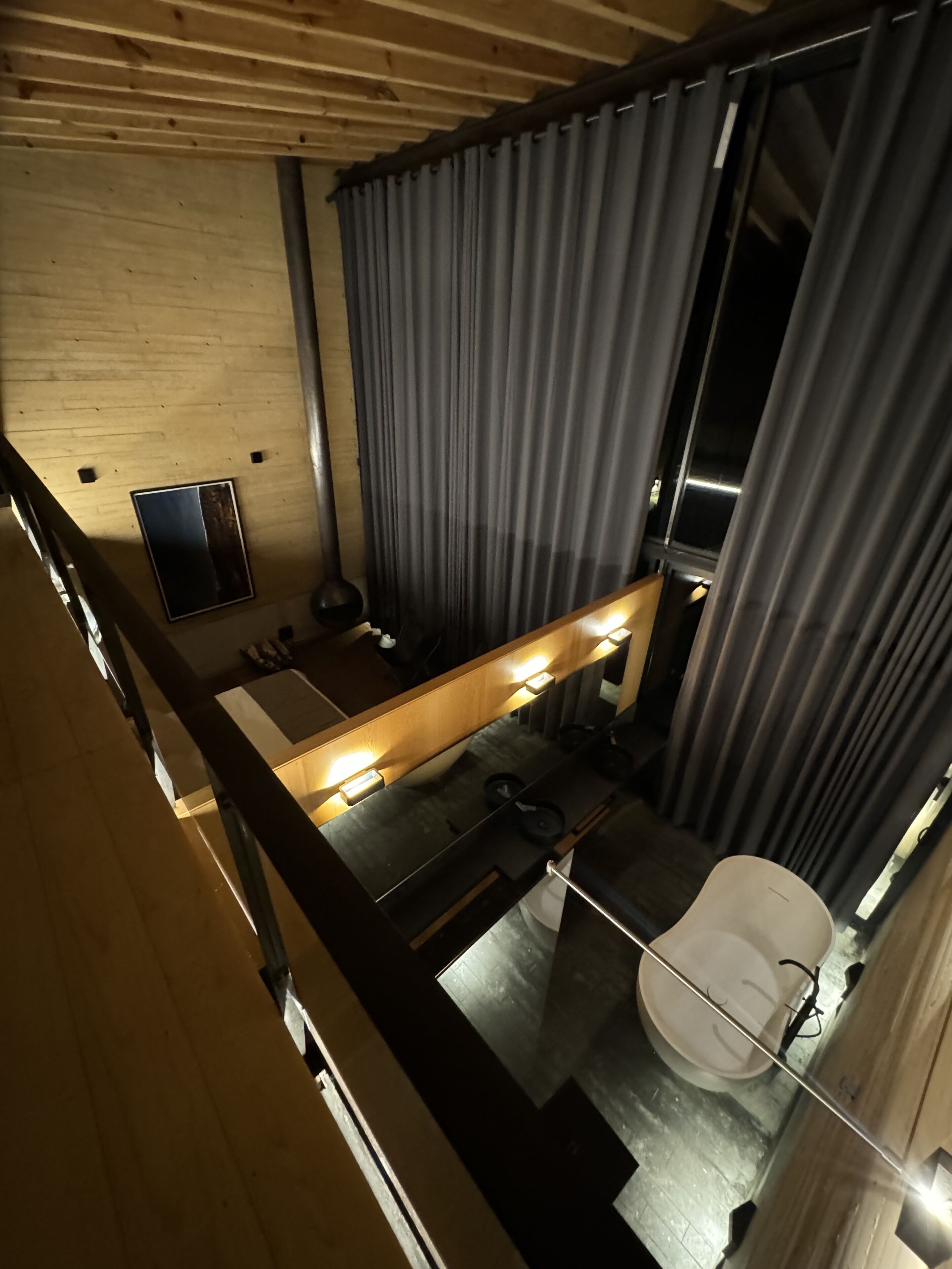 Une salle de bain moderne avec un plafond en bois, un grand miroir, des toilettes et un espace douche.