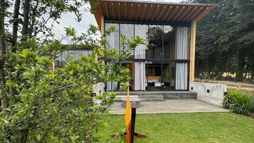 Ein modernes Haus mit großer Glasfassade, einer Holzpergola und einem gepflegten Rasen.