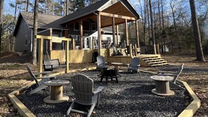 Une cabane dotée d’un porche couvert, de meubles d’extérieur et d’un foyer.