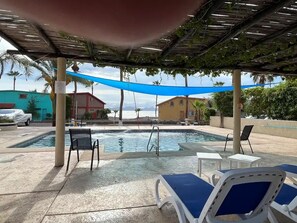 Uma área de piscina com espreguiçadeiras e um espaço de estar coberto.