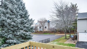 A residential area with a snow-covered evergreen tree, a paved driveway, and a house with a garage. - Welcoming Condo in Davenport: Central Location! (Davenport)