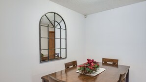 A dining room with a wooden table, four chairs, and a mirror on the wall. - Welcoming Condo in Davenport: Central Location! (Davenport)
