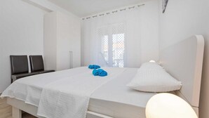A bedroom with a large bed, a bedside lamp, and two chairs.
