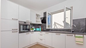 A modern kitchen with white cabinets, a built-in oven, a window with a view, and a black countertop.