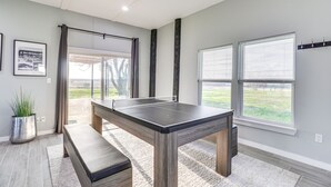 A ping pong table in a room with large windows, a bench, and a potted plant. - Modern Farmhouse in Del Valle: Rural Setting! (Del Valle)