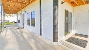 A covered porch with a concrete floor, a white garage door, and a wooden ceiling structure. - Modern Farmhouse in Del Valle: Rural Setting! (Del Valle)