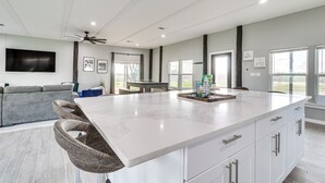 A spacious kitchen with a large island, white cabinetry, and a ceiling fan. - Modern Farmhouse in Del Valle: Rural Setting! (Del Valle)