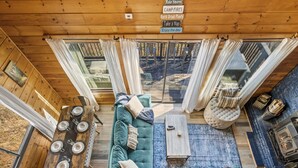 A cozy cabin interior with a wooden ceiling, a sofa, a dining table with cups, and a sign with activities. - Epic Views| 3 Pools!| Dog Friendly| Gatlinburg, GSMNP 10 Minutes (Gatlinburg)
