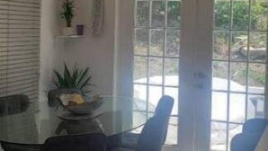 A dining area with a glass table, black chairs, and a modern chandelier. - Hervana's Casa Blanca (St. Thomas)