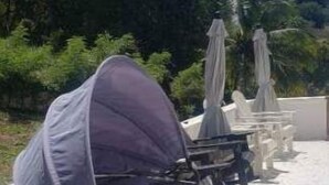 A sunbed with a canopy, a lounge chair, and an umbrella in a garden setting. - Hervana's Casa Blanca (St. Thomas)