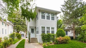 A two-story residential building with a front entrance, a small porch, and a well-maintained lawn. - Peaceful Spacious 1BR w Sunroom! - mins to metro (Alexandria)