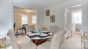 A dining room with a round table, chairs, and a small side table. There are two framed pictures on the wall. - Spacious 2BR 2Level Apt - Walkable to metro! (Alexandria)