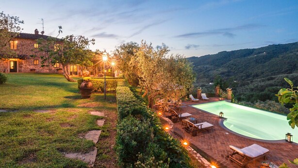 Une maison en pierre avec une piscine, entourée d’un jardin et offrant une vue sur un paysage vallonné.