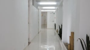 A long, narrow hallway with white walls and a shiny tiled floor. - HOTEL CASA NATURA  (Pereira)