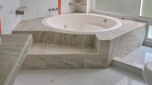 A modern bathroom with a freestanding bathtub, a window with frosted glass, and a tiled floor. - HOTEL CASA NATURA  (Pereira)