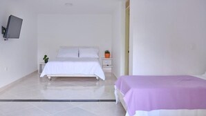 A bedroom with a bed, a bedside table, a small potted plant, and a wall-mounted TV. - HOTEL CASA NATURA  (Pereira)