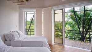 A room with two beds, large windows, and a view of greenery outside. - HOTEL CASA NATURA  (Pereira)