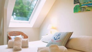 Un dormitorio con cama, almohadas, una silla y un cuadro.