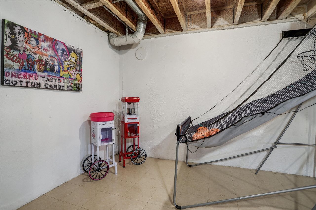 A room with a white wall, a colorful poster, a red and white cart, and a metal ladder.