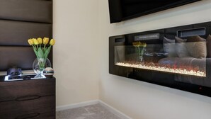 A modern room with a large aquarium, a dark wooden dresser, and a flat-screen TV mounted on the wall. - FamilyNest/King Bd/GameRoom (Royal Oak)