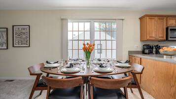 A dining area with a round table set for four, surrounded by wooden chairs.