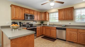 Una cocina con armarios de madera, microondas, estufa, fregadero y lavavajillas.