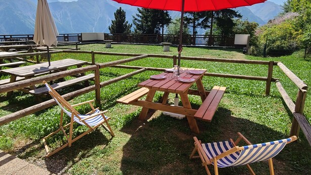 A picnic setup with a red umbrella, wooden benches, and striped beach chairs. - Studio 4/6pers, Terrasse, Jardinet, vue Imprenable sur la Muselle.50m des Pistes (Les Deux Alpes)