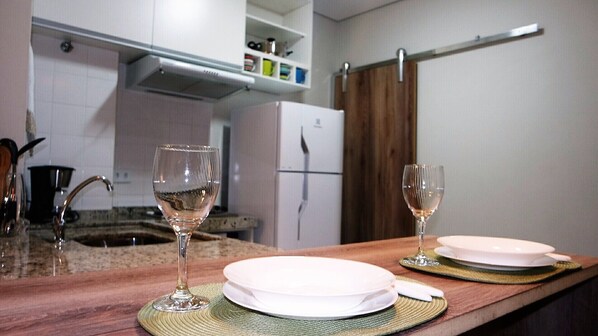 Een koelkast, een magnetron, een kookplaat, kookgerei, borden en bestek