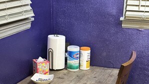 Pieni ruokailutila, jossa on puinen pöytä ja tuolit, paperinenäliöpakkaus, Clorox-desinfiointiaineen pullo ja kulho.
