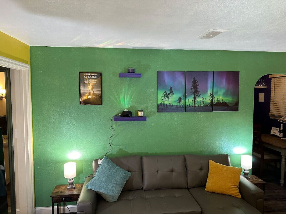 A living room with a green wall, a brown sofa, two lamps, and a coffee table.