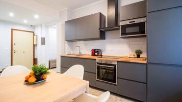 Eine moderne Küche mit grauen Schränken, einer Holz Arbeitsplatte, einem eingebauten Backofen und einer schwarzen Dunstabzugshaube.