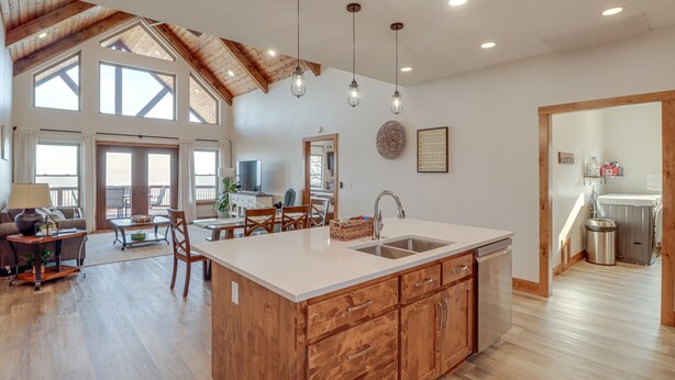 Una cocina amplia con una isla grande, muebles de madera y un techo alto con vigas a la vista.