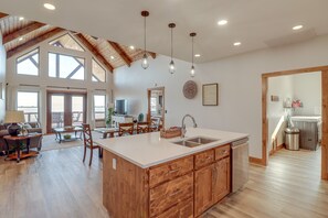 A spacious kitchen with a large island, wooden cabinetry, and a high ceiling with exposed beams. - Spacious Harrison Vacation Rental w/ Deck & Views! (Harrison)