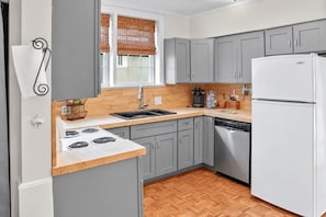A modern kitchen with grey cabinets, a white refrigerator, a wooden countertop, and a window with blinds. - Simplicity on Sims | 3BR 1BA | Downtown (Columbia)