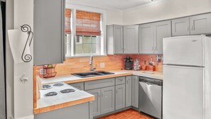 A kitchen with grey cabinets, a white refrigerator, a wooden countertop, and a window with blinds. - Simplicity on Sims | 3BR 1BA | Downtown (Columbia)