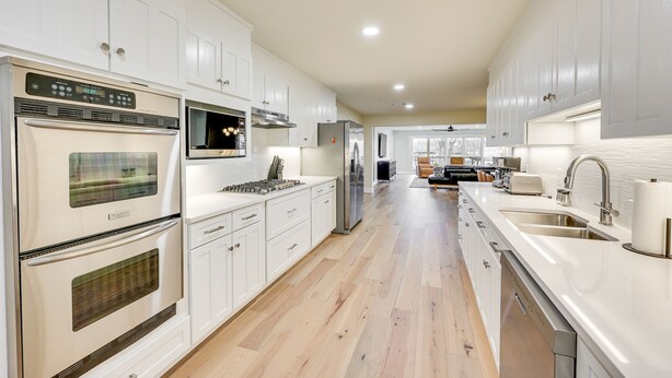 A modern kitchen with white cabinetry, stainless steel appliances, and a wooden floor. - Grand Lakefront Home in Hot Springs w/ Boat Dock! (Hot Springs)