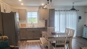A modern kitchen with a dining area, wooden flooring, and white cabinetry. - Otter House
Close to the Beach (Tulameen)