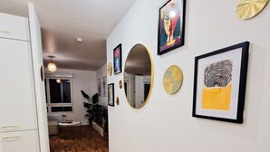 A hallway with wooden flooring, white walls, and various framed artworks. - Charming Apartment With Panoramic Seine River & Eiffel Tower Views (Ivry-sur-Seine)