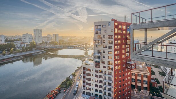 A high-rise building with multiple floors, a river in the background, and a bridge. - Charming Apartment With Panoramic Seine River & Eiffel Tower Views (Ivry-sur-Seine)