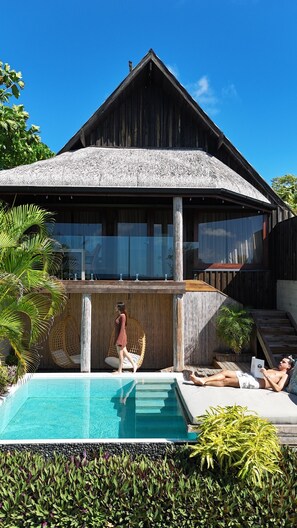 A wooden villa with a swimming pool, a covered outdoor seating area, and lush greenery. - Bombua Beach House (Luganville)