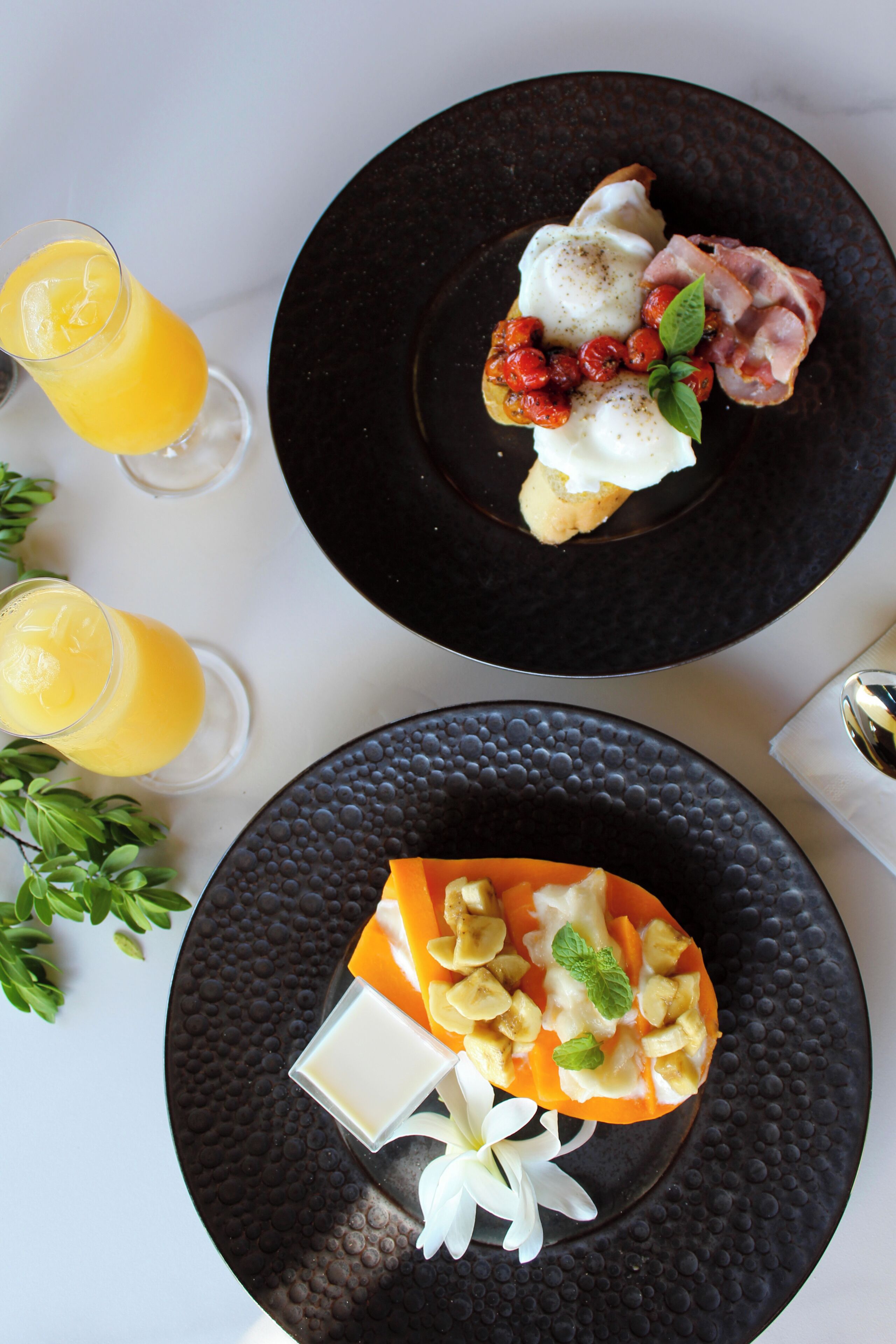 Two plates of food with a glass of orange juice.