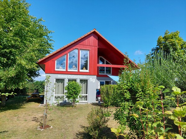 A red and white house with the number 59 and the name "Haus Ostseeblick" on the facade. - Erholungszeit im Haus Ostseeblick (Kalkhorst)