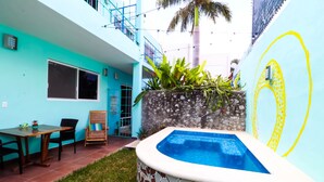 A turquoise building with a tiled pool, a dining area, and a staircase.