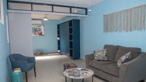 A living room with a blue chair, a grey sofa, a coffee table, and a bookshelf.